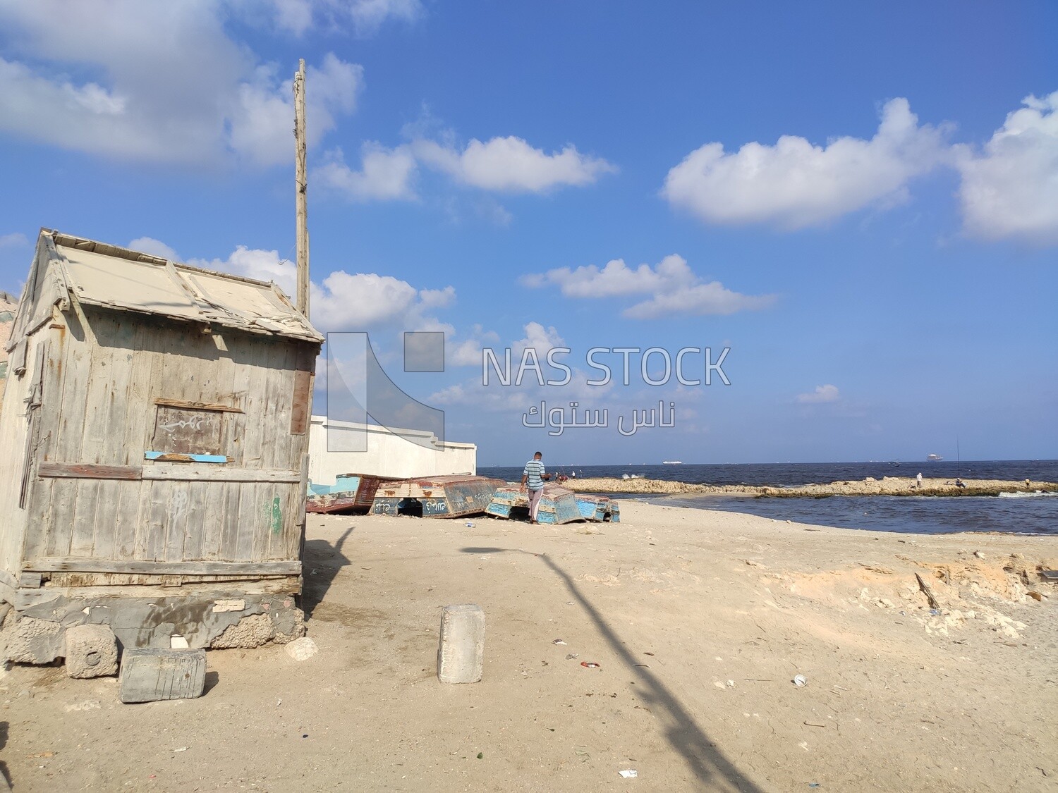 Small cabin on the beach with a bunch of broken boats on the beach