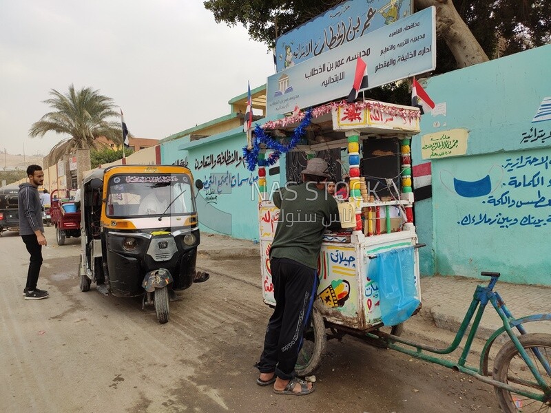 Peddler of ice cream stands in front of a school in Egypt