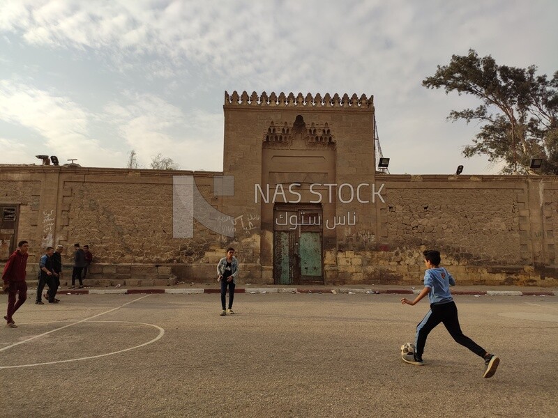 Egyptian child plays ball in the square in front of a cemetery in a city called "City of the Dead" in Egypt