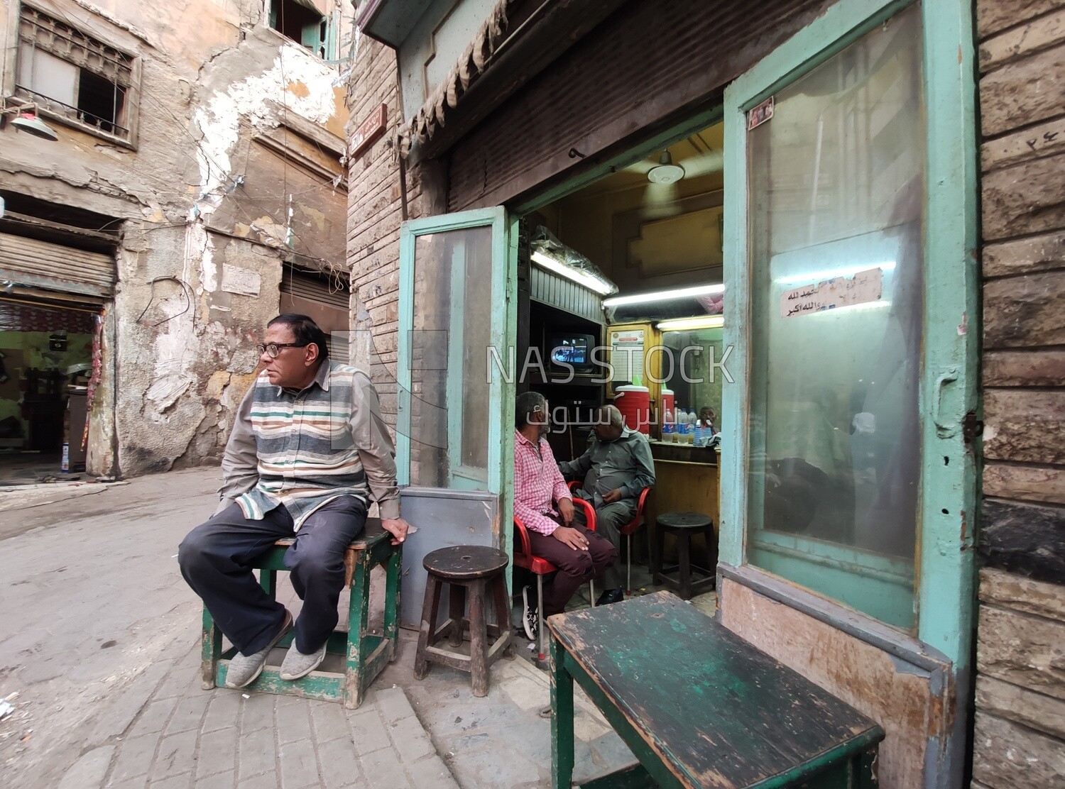 Man waits his turn in front of an old barber shop in one of Cairo&#39;s old neighborhoods