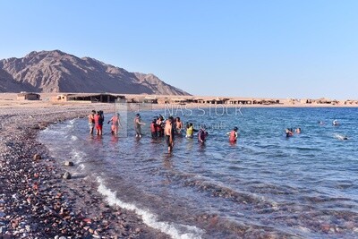 شاطئ البحر فى منتجع سياحى مزدحم بالاشخاص الذين يستمتعون بالسباحة و النشاطات الصيفية