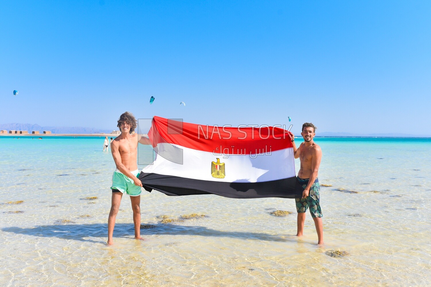 Two young men carrying the Egyptian flag on the shore of the Red Sea