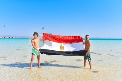 Two young men carrying the Egyptian flag on the shore of the Red Sea