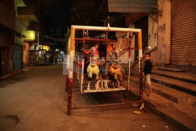Boy sitting on the swing in the street, Ramadan nights