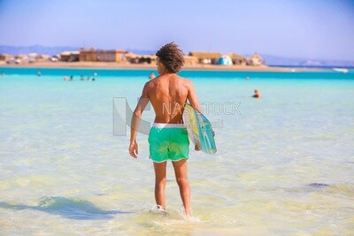 Young man in a swimsuit holding a surfboard