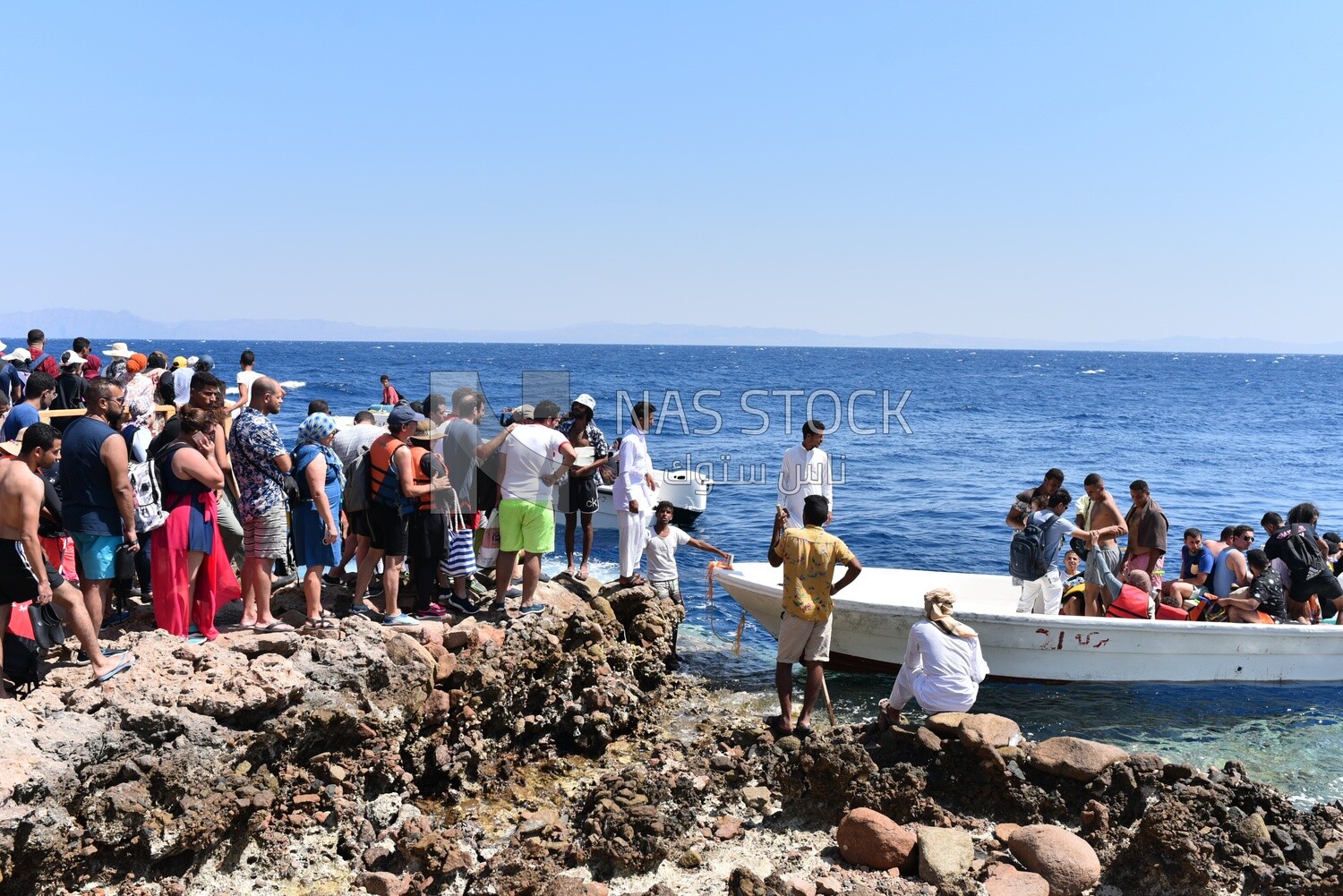 Summer vacationers board a small boat to go out on the sea and take a cruise, Dahab, Egypt.