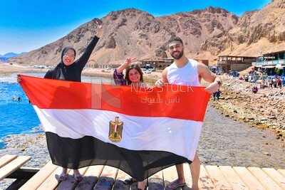 Group of friends raising the Egyptian flag on the beach