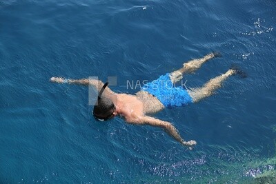 Guy wearing swimming goggles swims in the water