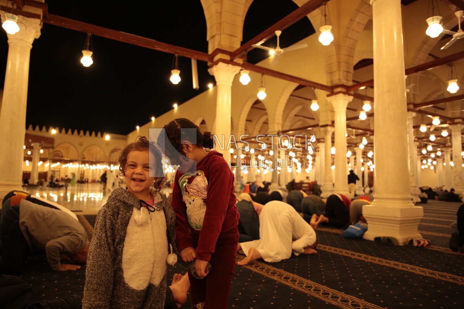 Two girls standing in a mosque, performing the obligatory prayer in the mosque, worship and draw close to God