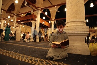 Boy in the mosque holding the holy Quran, performing the obligatory prayer in the mosque, worship and draw close to God
