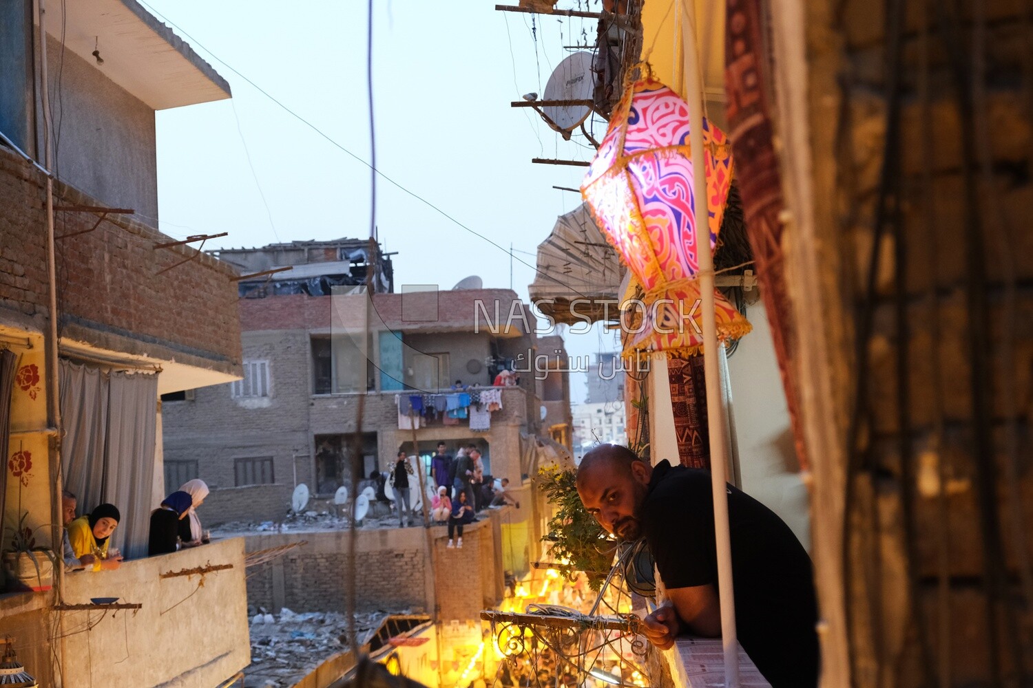 Man sitting on the Balcony wall watching the iftar in  Matareya, Ramadan Kareem, preparing their iftar, sharing their iftar