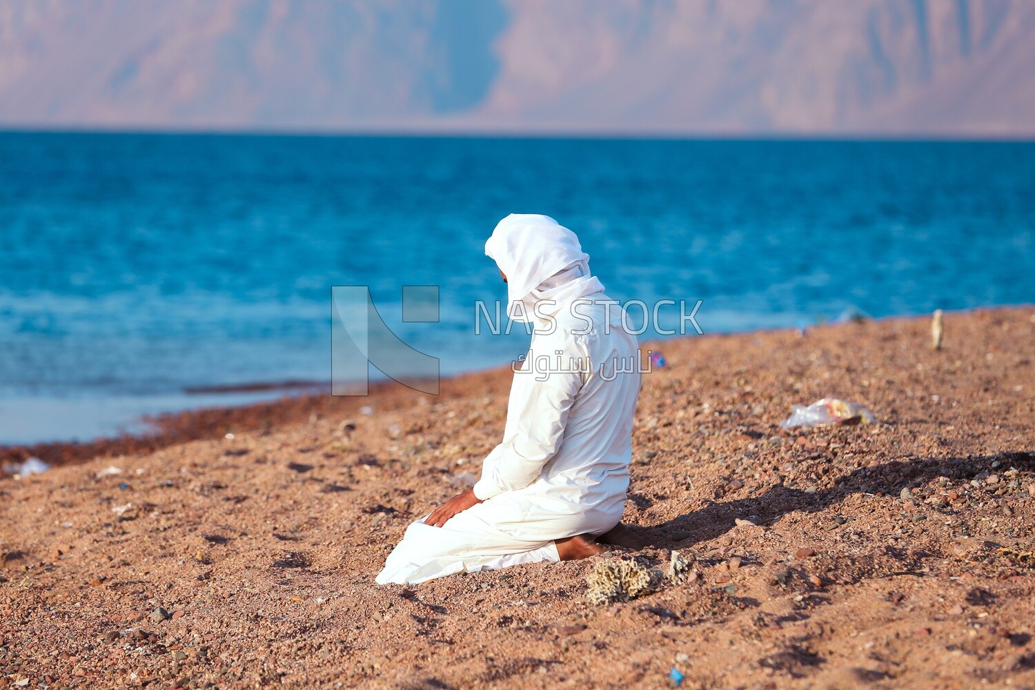 Man prays on the beach in front of the sea