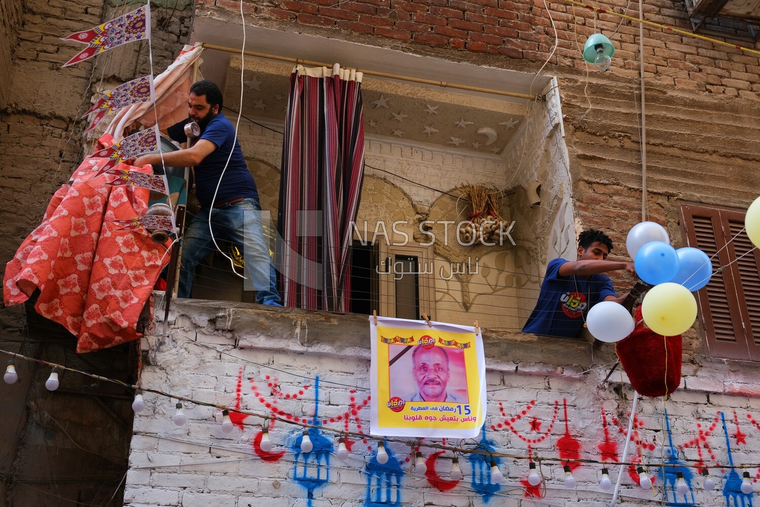 Two men standing on the balcony hanging decorations, Ramadan Kareem, preparing breakfast