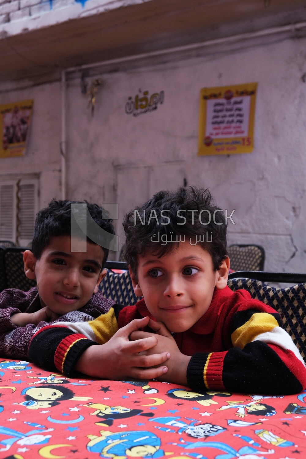 Two boys sitting at the table in iftar al-Matareya, Matareya sharing their iftar together in the street, Ramadan Kareem, preparing their iftar