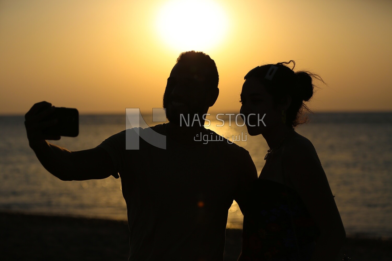 Two lovers taking a selfie at sunset