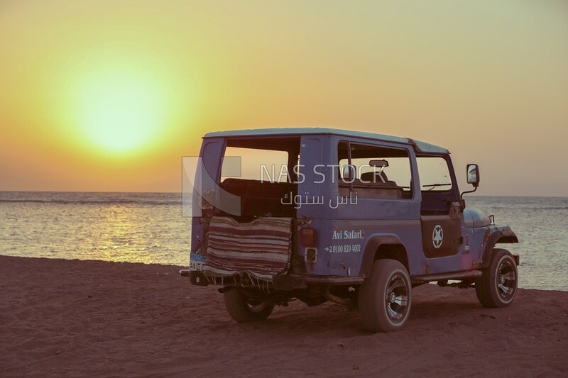 Safari car parked on the beach at sunset