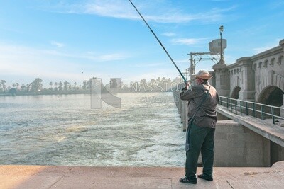 Adult man catches fish with a hook in the Nile River, Egypt