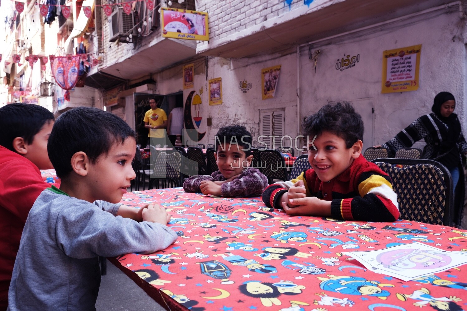 Boys sitting at the table in iftar al-Matareya, Matareya sharing their iftar together in the street, Ramadan Kareem, preparing their iftar
