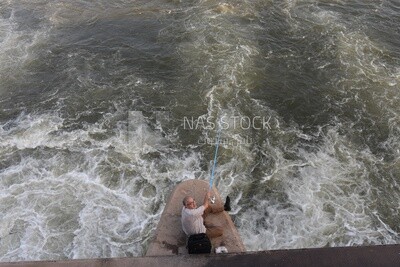 Adult man catches fish with a hook in the Nile River, Egypt