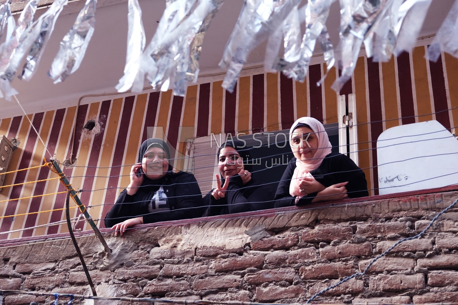 Women standing on the balcony watching the preparing of the iftar, Ramadan Kareem, preparing their iftar