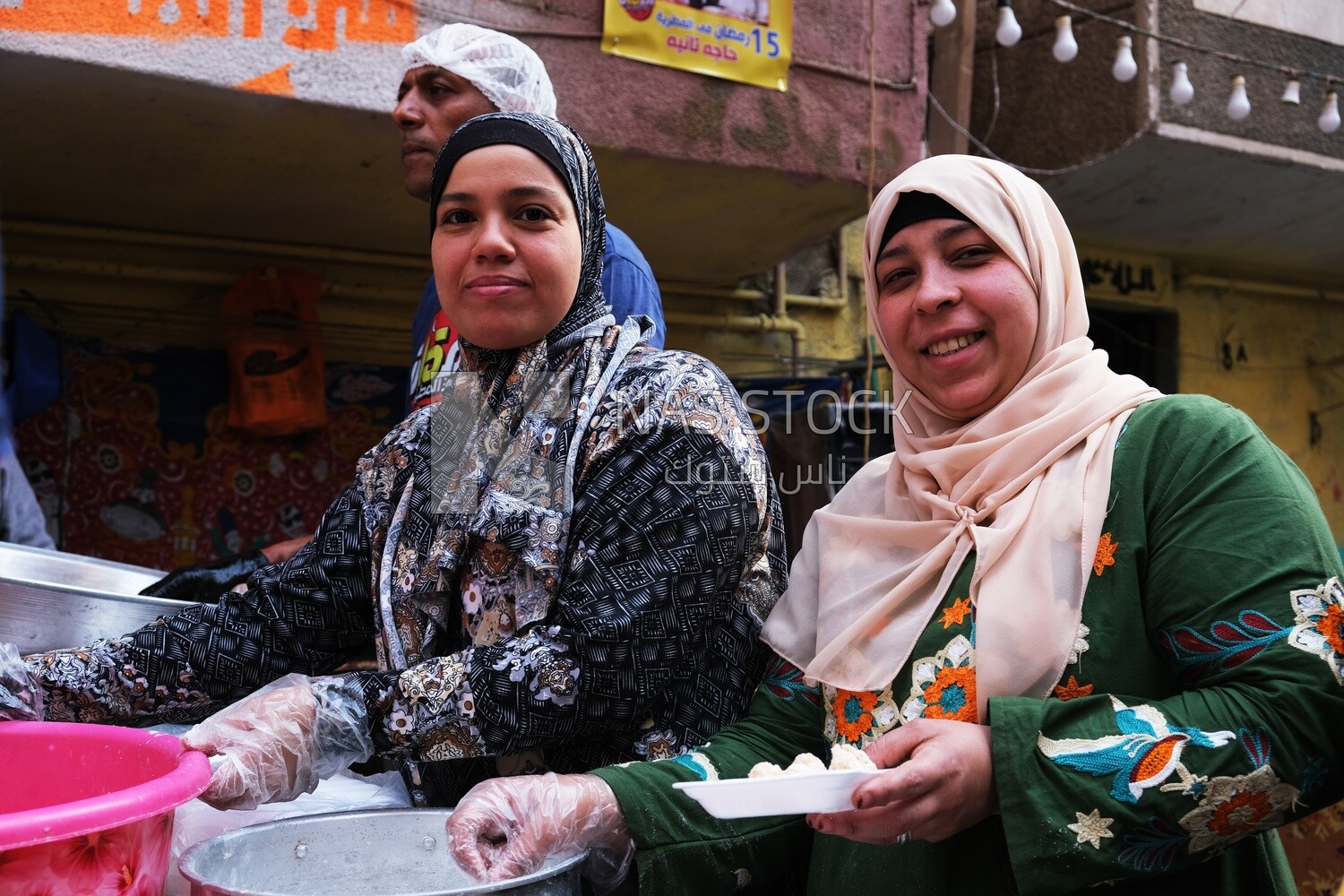 Women standing in the street taking a photo during the iftar on Matareya, Ramadan Kareem, preparing their iftar