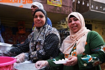 Women standing in the street taking a photo during the iftar on Matareya, Ramadan Kareem, preparing their iftar
