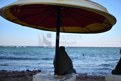 Muslim woman sitting under the pergola on the seashore