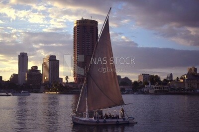 Picture showing a sailboat passing in the Nile River in front of the Sofitel El Gezirah hotel  and the Sheraton Hotel