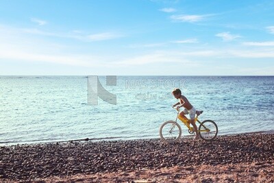 Child in a swimsuit riding his bicycle