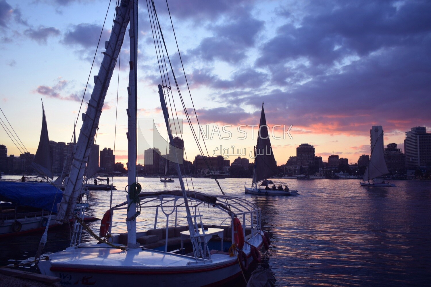 Picture showing the details of the Nile felucca moored in the Nile River and other sailboats roaming in the Nile River