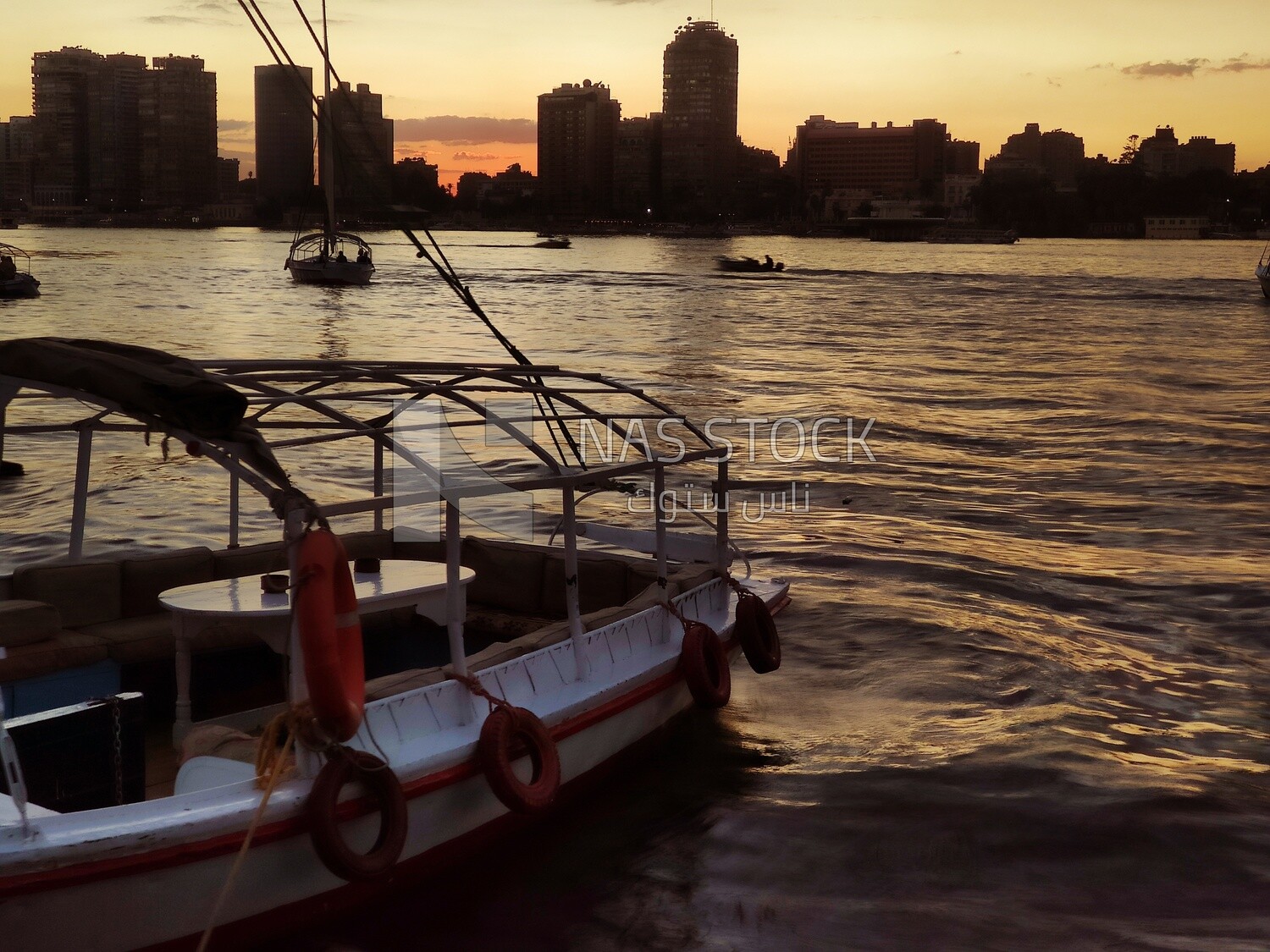 Picture showing a felucca moored in the Nile River and another sailing