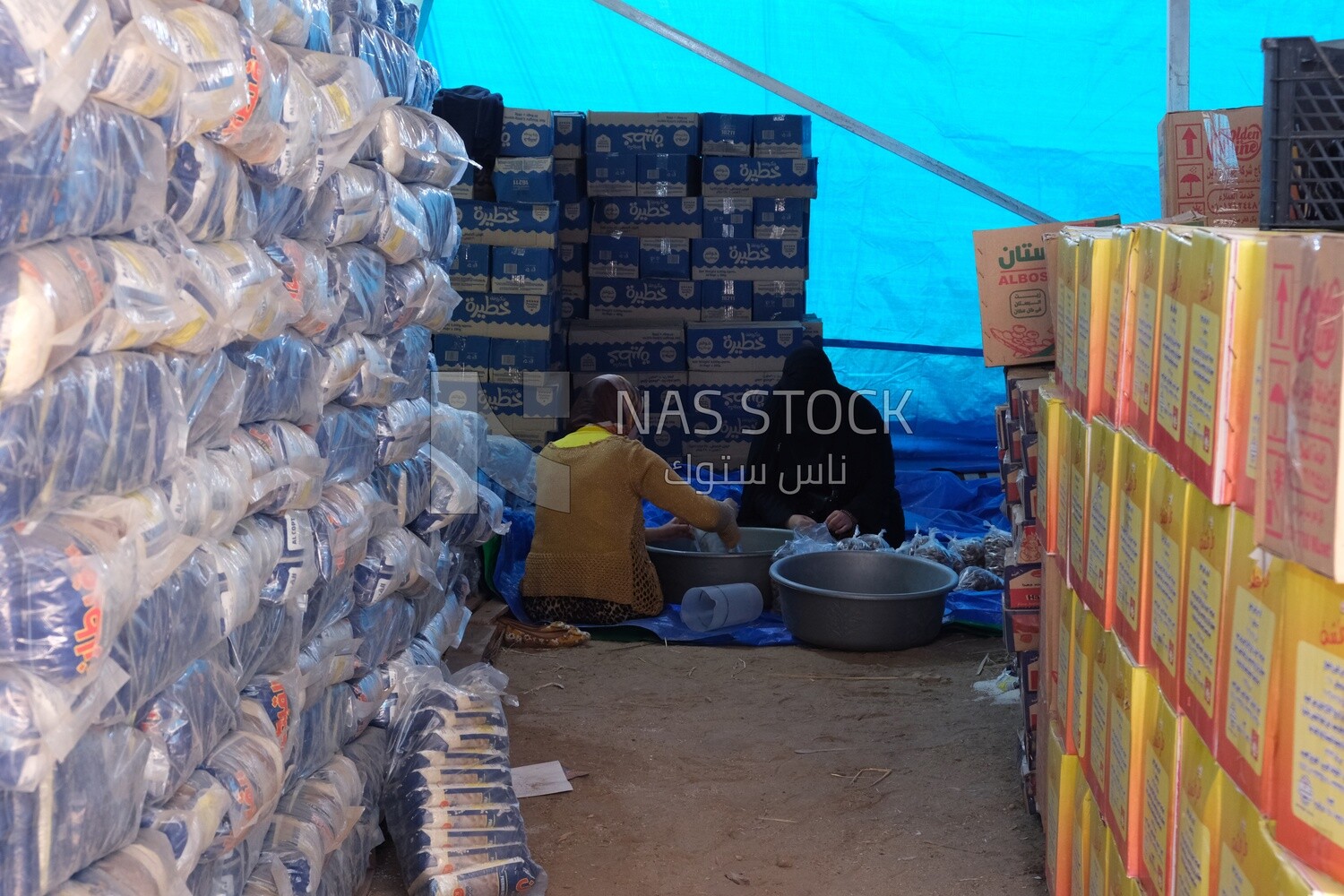 Two Egyptian women collect bags of legumes to put them in food bags for the poor