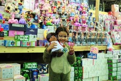 Girl standing in the street holding a doll in front of a lanterns store, Sayeda Zainab, Ramadan Kareem