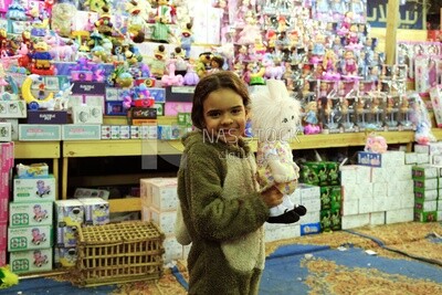 Girl standing in the street holding a doll in front of a lanterns store, Sayeda Zainab, Ramadan Kareem