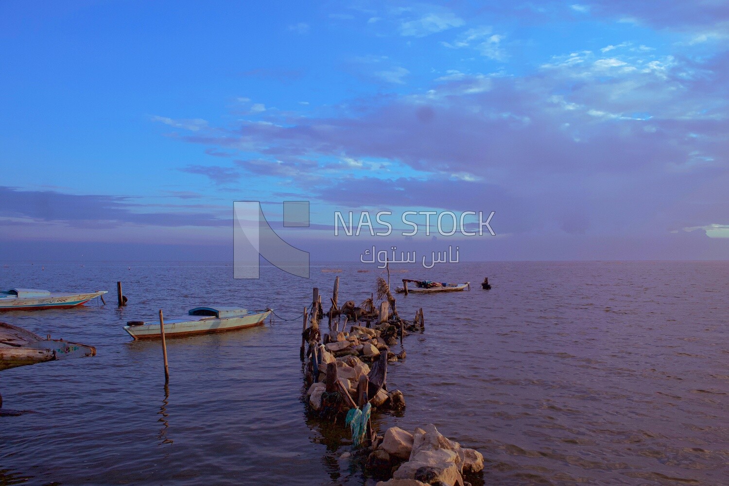 Old fishing boats next to rocks and  timber inside the sea water