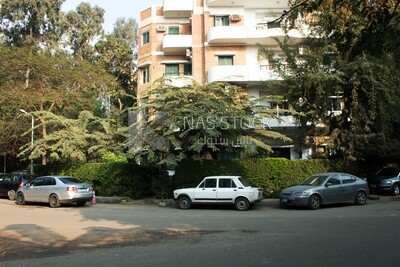 Cars parked at a large house in Maadi surrounded by trees and plants