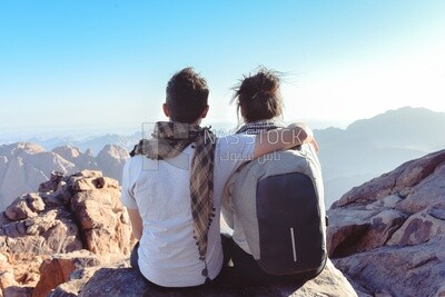 Couple sits together in unison watching the sunset