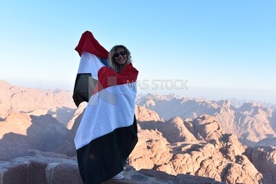 Girl raises the Egyptian flag above one of the mountain peaks, Egypt