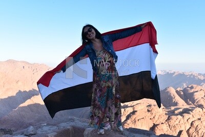 Girl raises the Egyptian flag above one of the mountain peaks, Egypt