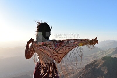Girl holding her scarf enjoying from the highest mountain peak