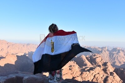 Girl raises the Egyptian flag above one of the mountain peaks, Egypt