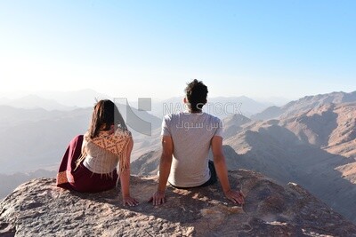 Two lovers sitting together enjoying the natural scenery from the highest mountain peak in the Sinai Peninsula, Egypt
