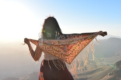 Girl holding her scarf enjoying from the highest mountain peak