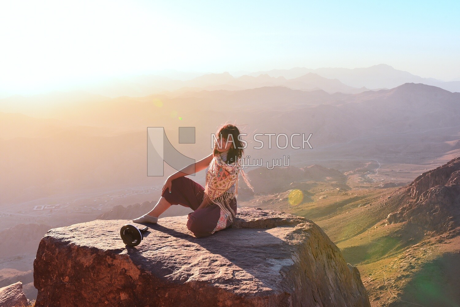 Woman sitting at edge of cliff looking over expansive view