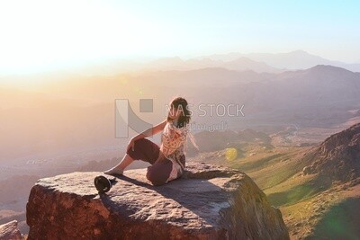 Woman sitting at edge of cliff looking over expansive view