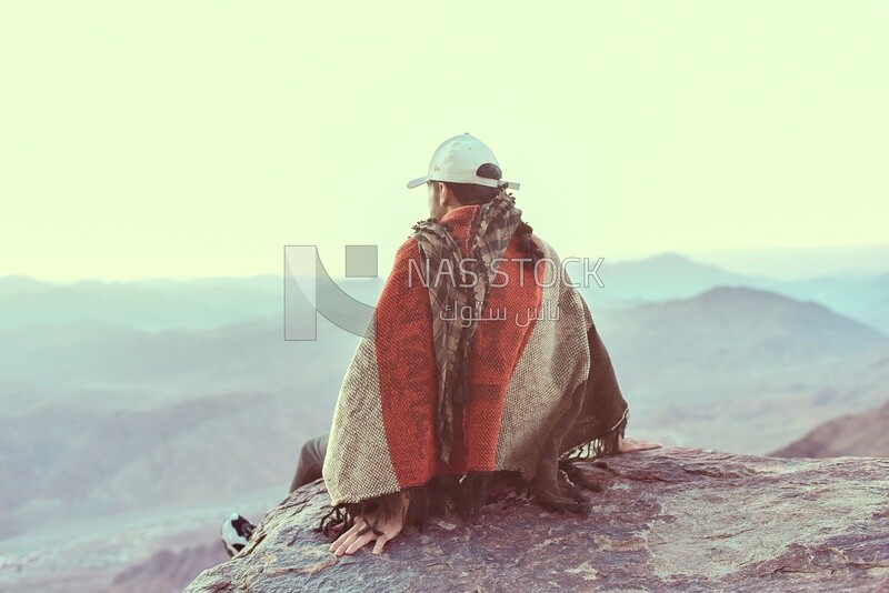 Young traveler sitting on the edge of a cliff