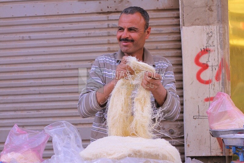 Man standing in the street selling konafa, Cart street, Ramadan vibes