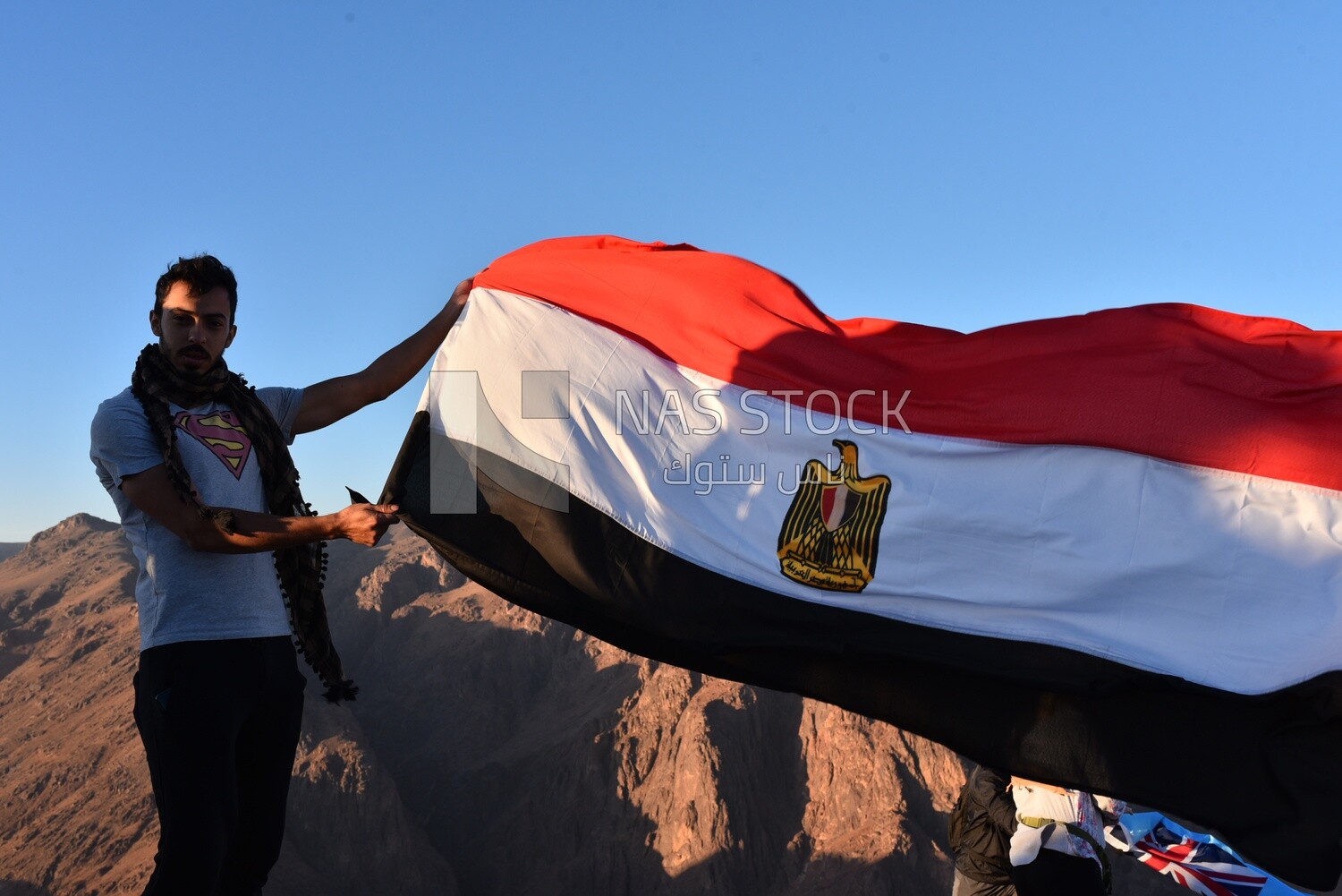 Man raises the Egyptian flag over the top of a mountain