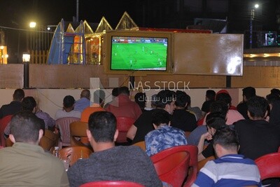 People sitting in a café watching the match on TV