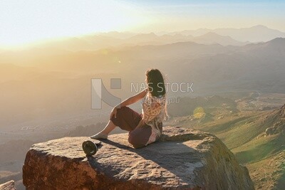 Woman sitting at edge of cliff looking over expansive view